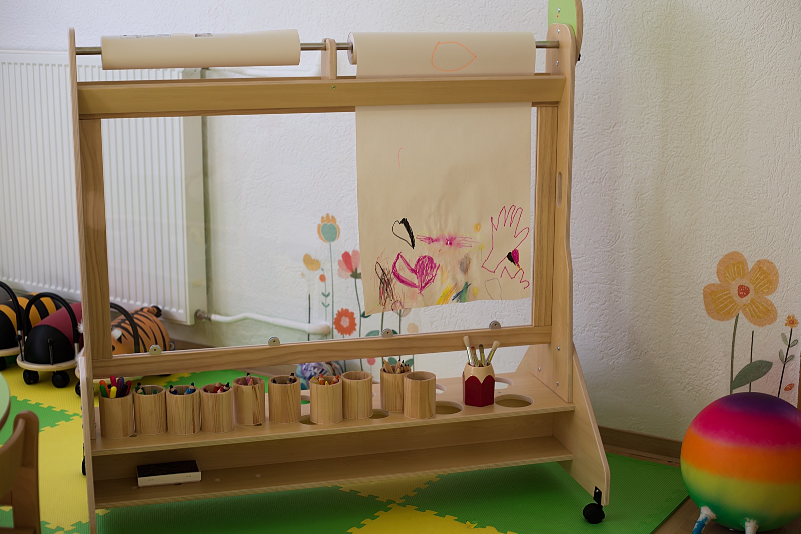 Kreativwerkstatt mit Holzstaffelei, Papierrollen und bunten Stiften